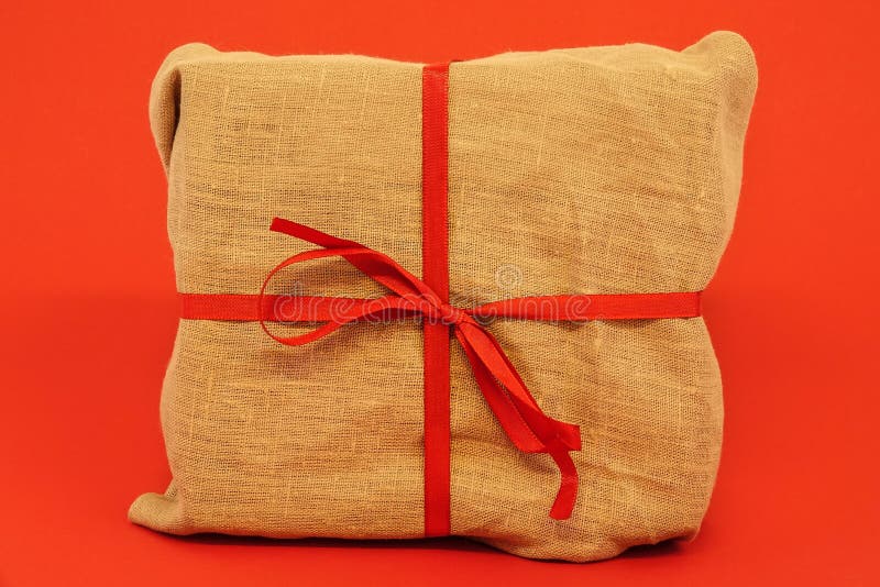 Bożenarodzeniowy prezenta pudełko na czerwonym tle Burlap kanwy opakowanie zdjęcia stock Bożenarodzeniowy prezenta pudełko na czerwonym tle Burlap kanwy opakowanie zdjęcia stock