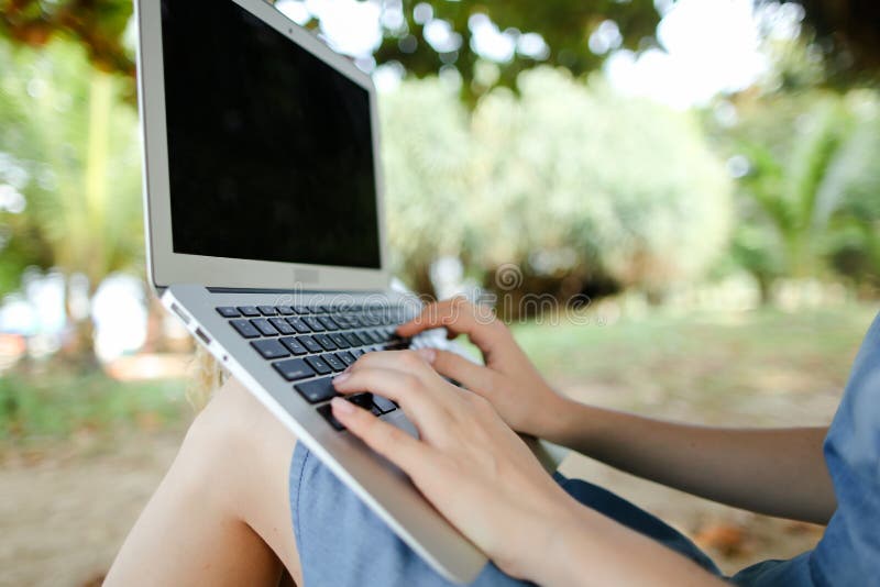 Braccia femminili con laptop con sabbia sullo schermo nero di fondo. immagini stock