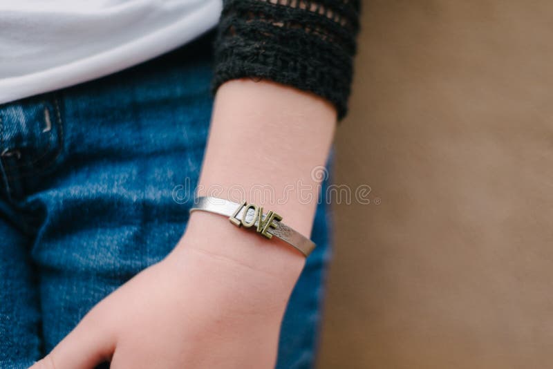 Braccialetto di amore sul polso della ragazza fotografia stock Braccialetto di amore sul polso della ragazza fotografia stock