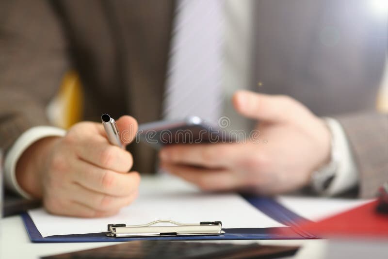 Braccio maschio nella penna del telefono e dell'argento della tenuta del vestito immagine stock Braccio maschio nella penna del telefono e dell'argento della tenuta del vestito immagine stock