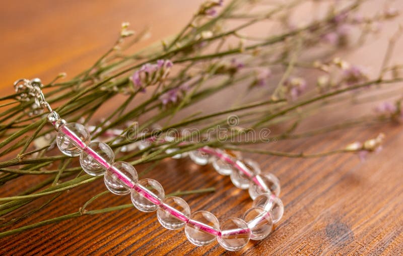 Bracelet et fleurs en cristal de quartz sur la table en bois images stock Bracelet et fleurs en cristal de quartz sur la table en bois images stock