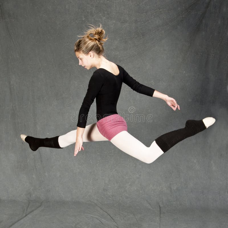 Female ballet dancer jumping and doing split, over gray background. Female ballet dancer jumping and doing split, over gray background