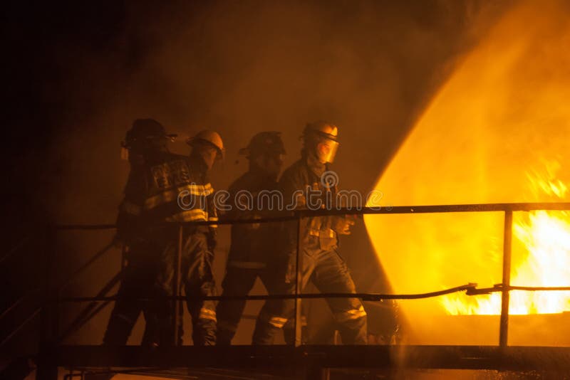 Brandbestrijders die volledige nevel gebruiken om een brand tijdens brandbestrijdingsoefening te doven