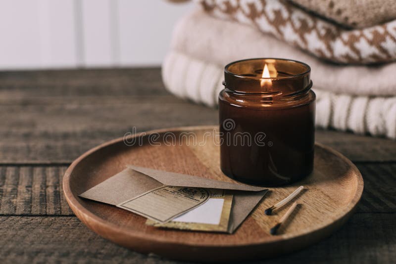 Brandende kaars in kleine amberkleurige glazen pot met houten baksteen voor snoepjes. concept van handige levensstijl