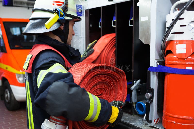 Brandman med vattenslangen på en firetruck royaltyfria foton Brandman med vattenslangen på en firetruck royaltyfria foton