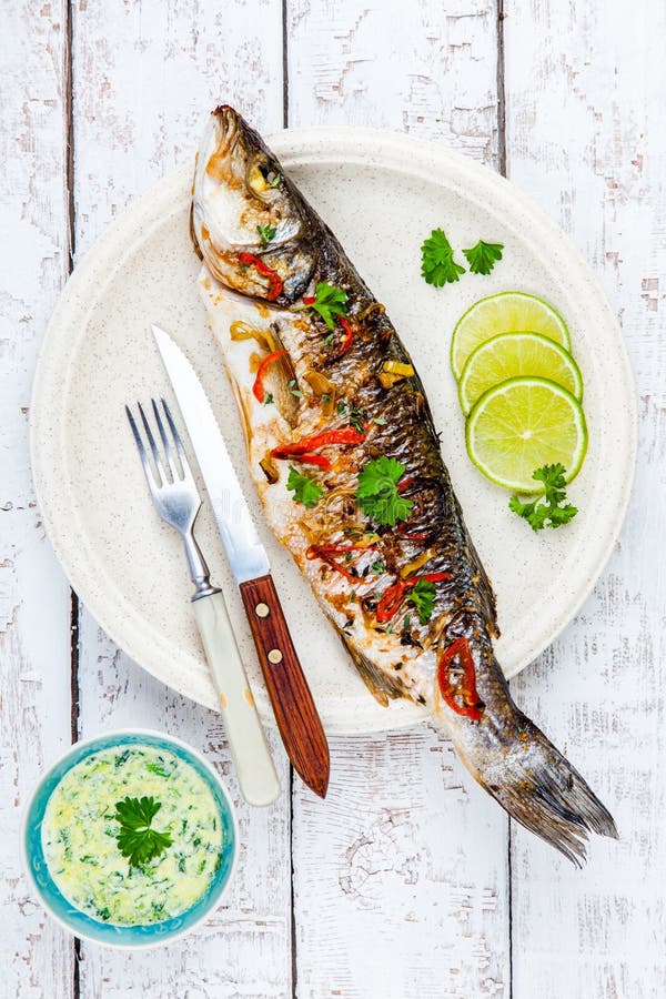 Branzino al forno del pesce con calce e prezzemolo immagine stock libera da diritti Branzino al forno del pesce con calce e prezzemolo immagine stock libera da diritti