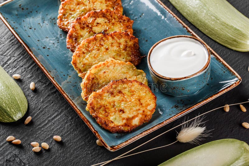 Braten von selbst gemachten Pfannkuchen von der Zucchini mit Sahne in der Platte auf dunklem Steinhintergrund Sauberes Essen stockfoto Braten von selbst gemachten Pfannkuchen von der Zucchini mit Sahne in der Platte auf dunklem Steinhintergrund Sauberes Essen stockfoto