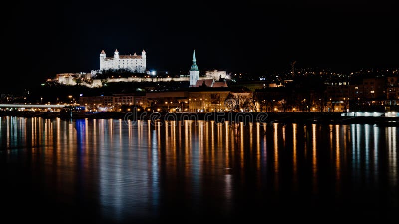 Temná nočná panoráma Bratislavy s odrazmi v rieke Dunaj