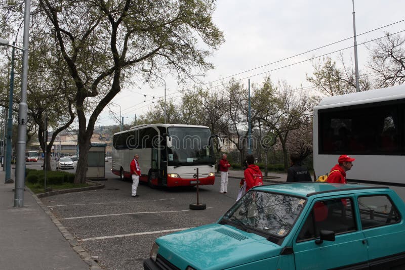 Bratislava, Slovakia - April, 2011: tourists in red jackets walk around their buses on bus stop near railway station. Bratislava, Slovakia - April, 2011: tourists in red jackets walk around their buses on bus stop near railway station