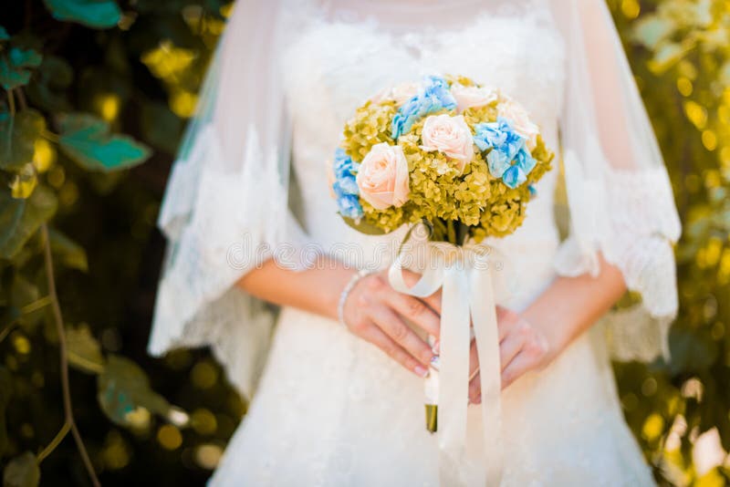 Braut in einem Kleid, das in einem grünen Garten steht und einen Hochzeitsblumenstrauß von Blumen und von Grün hält stockfotos Braut in einem Kleid, das in einem grünen Garten steht und einen Hochzeitsblumenstrauß von Blumen und von Grün hält stockfotos