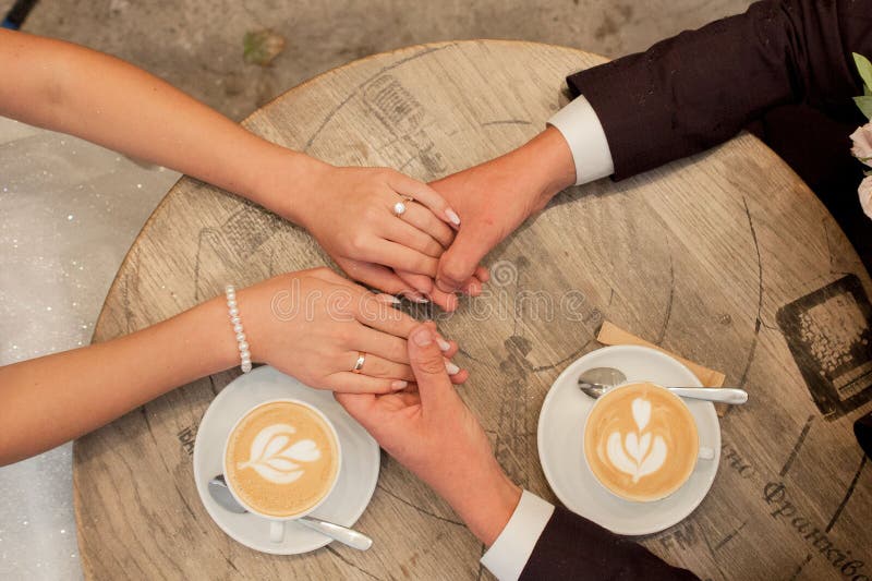 Braut- und Bräutigamgriffschalen mit Cappuccino und Blick auf einander lizenzfreies stockfoto Braut- und Bräutigamgriffschalen mit Cappuccino und Blick auf einander lizenzfreies stockfoto