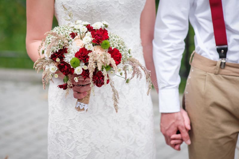 Bride and groom holding hands outdoors with bouquet. Bride and groom holding hands outdoors with bouquet