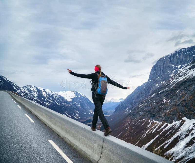 Brave Woman hiker walking to the cliff edge on mountain road, keeping balance. Brave Woman hiker walking to the cliff edge on mountain road, keeping balance