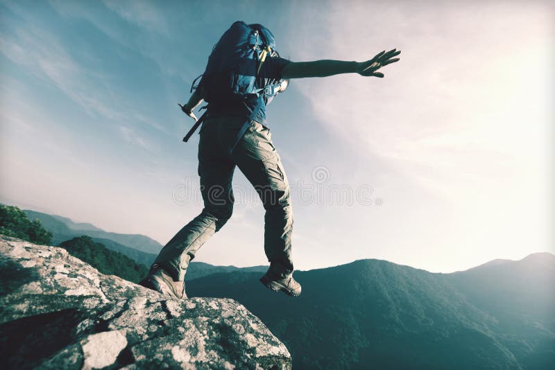 Brave woman hiker walking to the cliff edge on mountain top