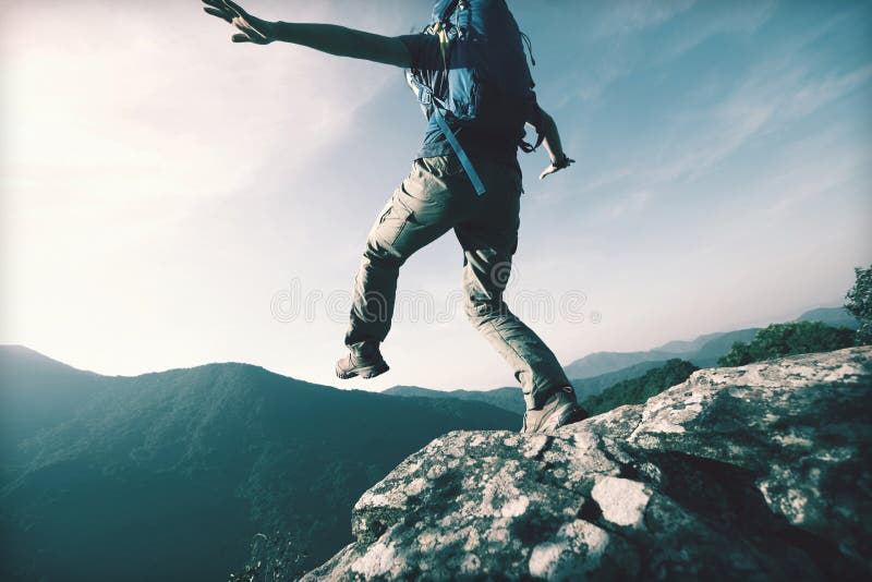 Brave woman hiker walking to the cliff edge on mountain top