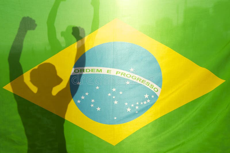 Shadow silhouette of man with arms raised behind Brazilian flag backlit by bright sun. Shadow silhouette of man with arms raised behind Brazilian flag backlit by bright sun