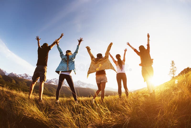 Group of happy friends stands against mountains sunset with raised arms and having fun. Group of happy friends stands against mountains sunset with raised arms and having fun