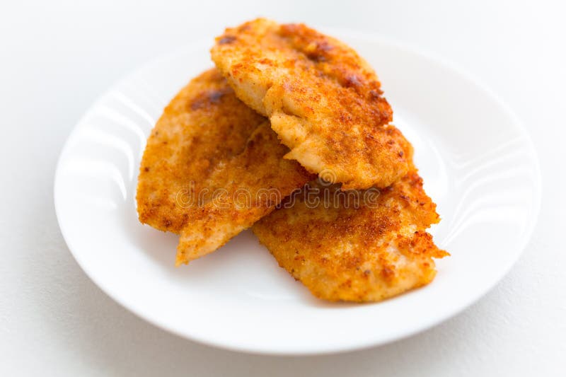 Bread crumb coated fried chicken breast on a white plate