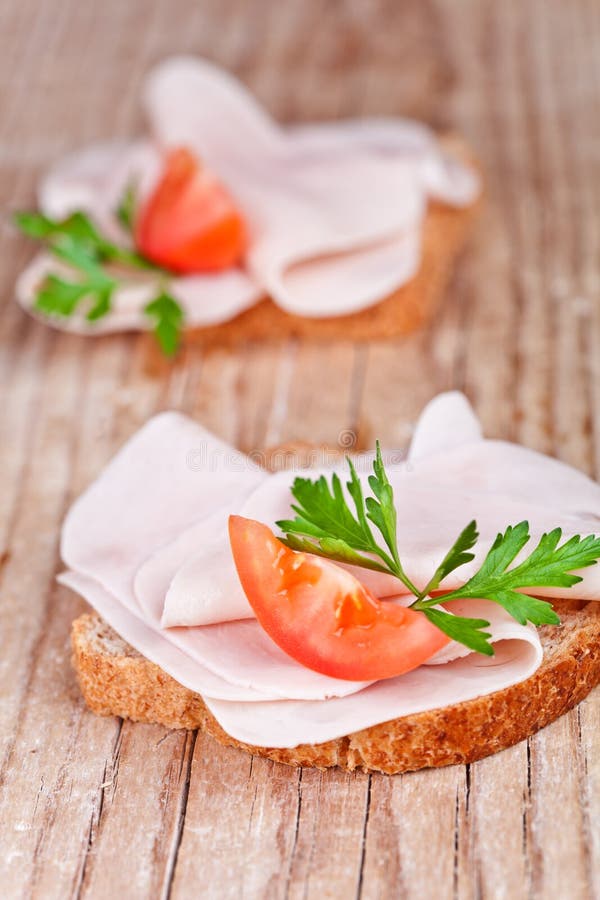 Bread with sliced ham, fresh tomatoes and parsley