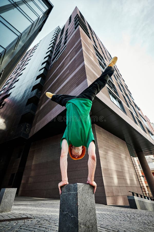 Breakdancer performs impressive handstand flip against modern urban backdrop, showcasing skills and athleticism in air. royalty free stock image