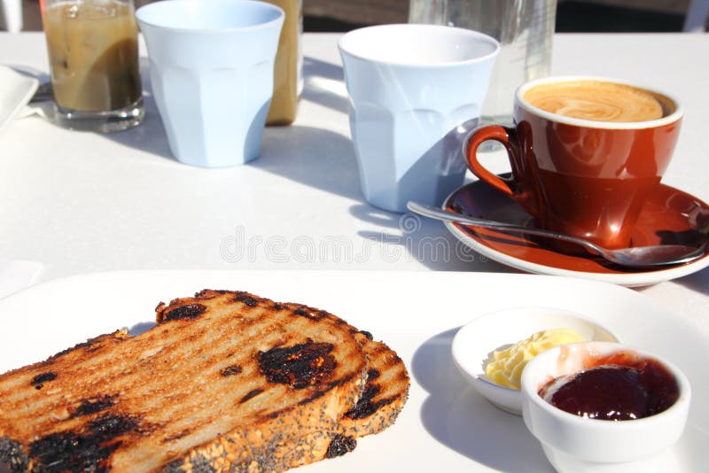 Simple breakfast with coffee, toast, butter and jam served outside