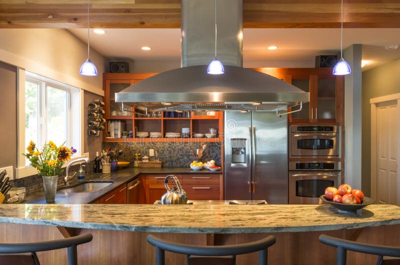 Breakfast bar in contemporary upscale home kitchen interior with granite countertops, vent hood and accent lighting