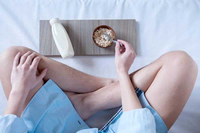 Breakfast in bed, a girl in a blue shirt sitting on a white sheet and Breakfast cereal with milk.