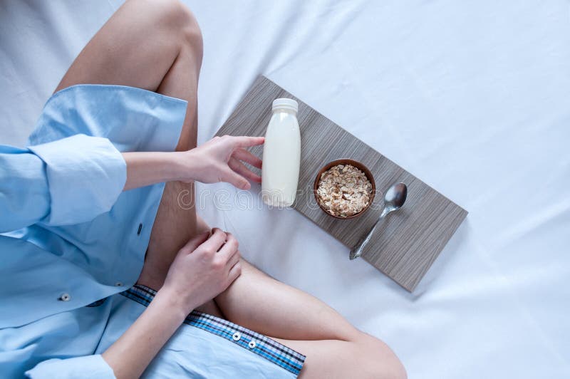 Breakfast in bed, a girl in a blue shirt sitting on a white sheet and Breakfast cereal with milk, healthy diet