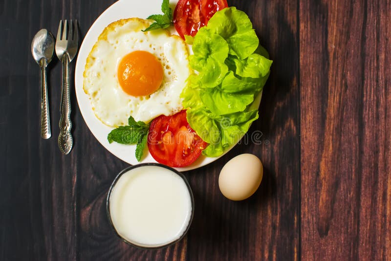Breakfast with Bread, Fried Eggs, Milk and Vegetables and Fried Tomato