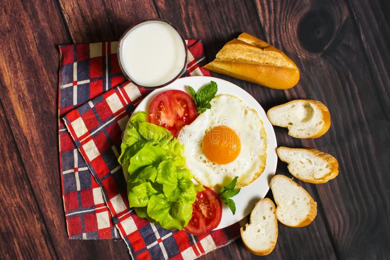 Breakfast with Bread, Fried Eggs, Milk and Vegetables and Fried Tomato
