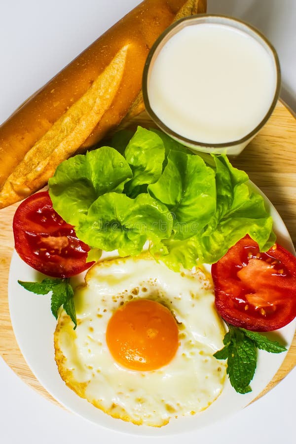 Breakfast with Bread, Fried Eggs, Milk and Vegetables and Fried Tomato