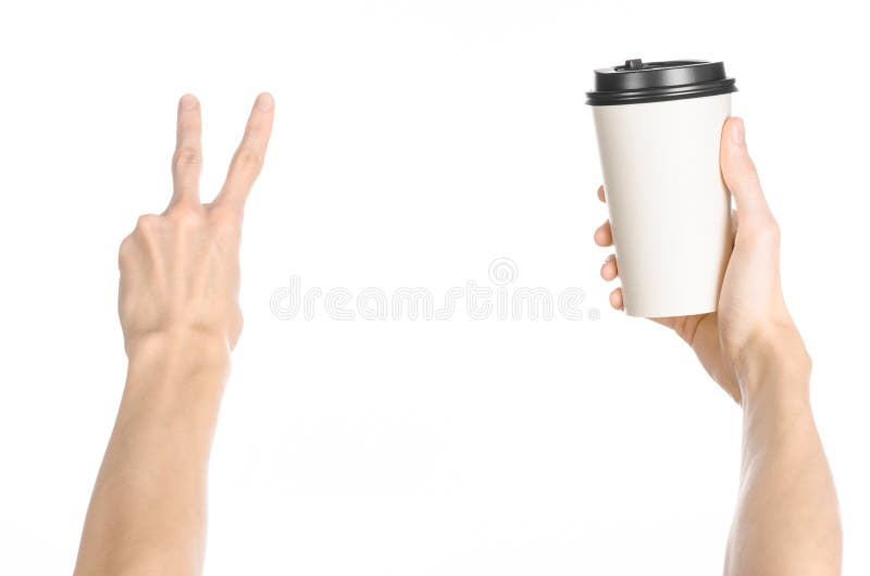 Breakfast and coffee theme: man s hand holding white empty paper coffee cup with a brown plastic cap isolated on a white backgroun