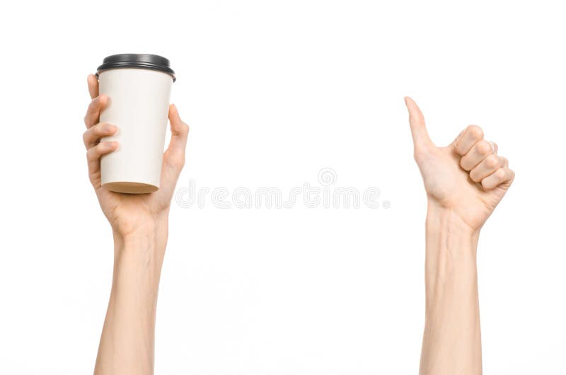 Breakfast and coffee theme: man s hand holding white empty paper coffee cup with a brown plastic cap isolated on a white backgroun