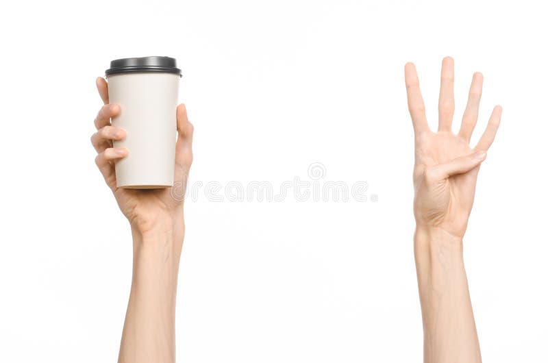 Breakfast and coffee theme: man s hand holding white empty paper coffee cup with a brown plastic cap isolated on a white backgroun