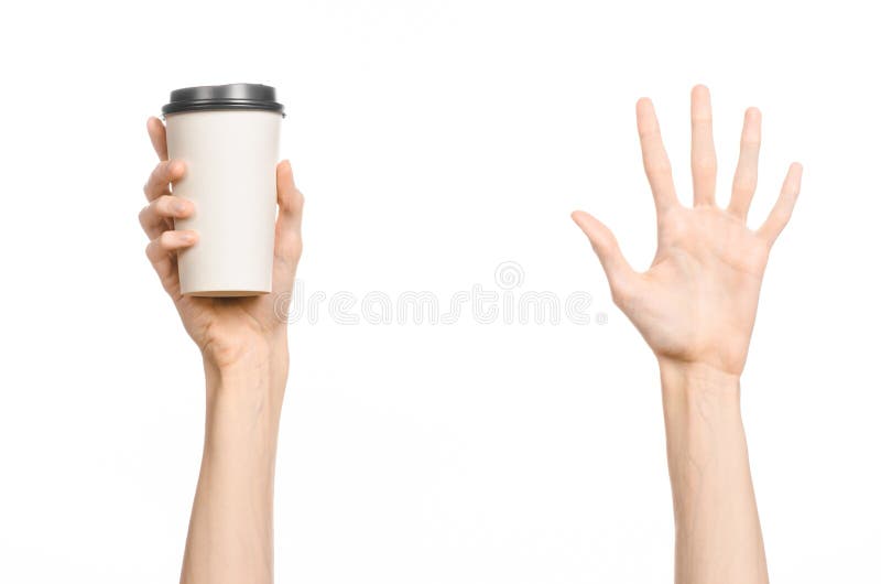 Breakfast and coffee theme: man s hand holding white empty paper coffee cup with a brown plastic cap isolated on a white backgroun