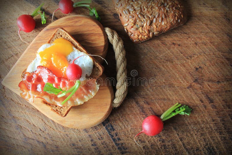 Breakfast , Crispy Bacon, Fried Eggs and Bread. Sandwich on Cutting Board. Rustic Table Stock