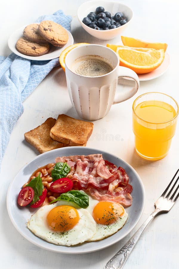 Breakfast with Fried Eggs, Bacon, Orange Juice, Yogurt and Toast Stock