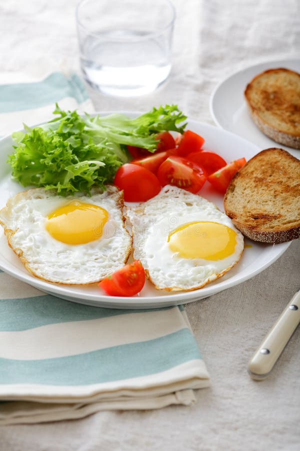 Breakfast Fried Eggs, Bread, Tomato and Lettuce on a Plate Stock