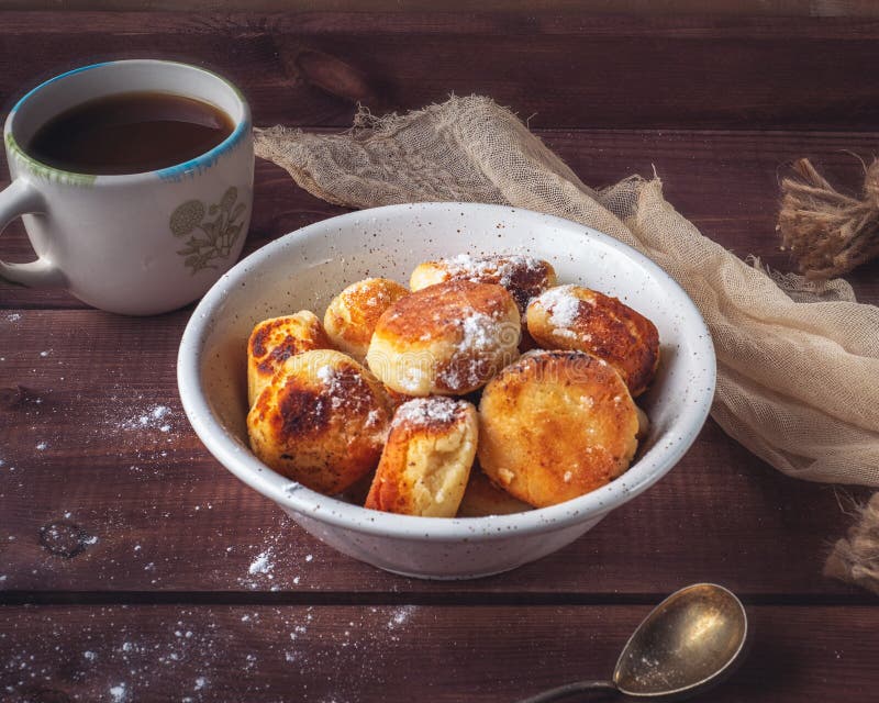 Breakfast with homemade cheesecakes with powdered sugar and tea on a wooden tray. Beige napkin and tea complement the composition stock photos Breakfast with homemade cheesecakes with powdered sugar and tea on a wooden tray. Beige napkin and tea complement the composition stock photos