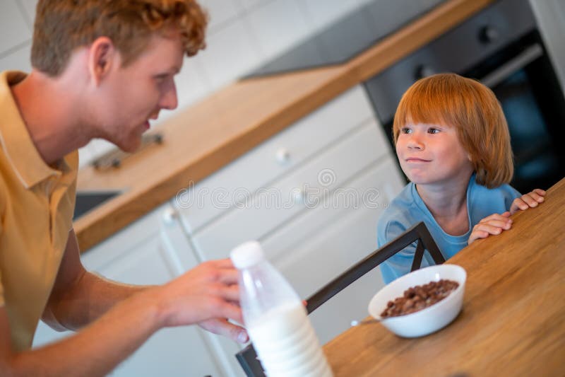 Man pouring milk into the plate of his son royalty free stock image