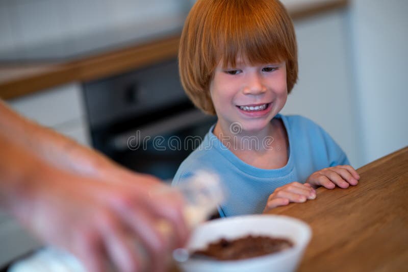 Man pouring milk into the plate of his son stock image