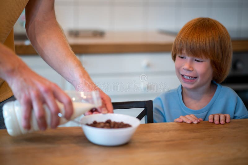 Man pouring milk into the plate of his son stock photography