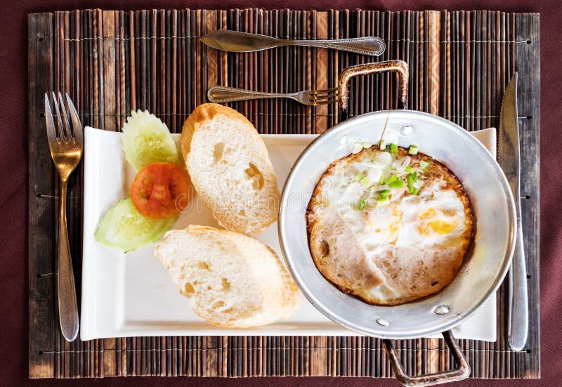 Breakfast Meal, Fried Eggs Pan and Breads on the Table Stock Photo