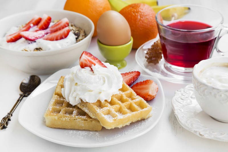 Breakfast meal with waffles, cream and strawberries, fresh fruit