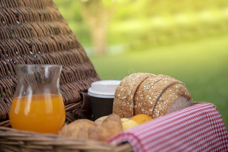 Breakfast pastry tasty with bread and orange juice on wooden picnic basket in the fresh green park. Soft sweet healthy organic