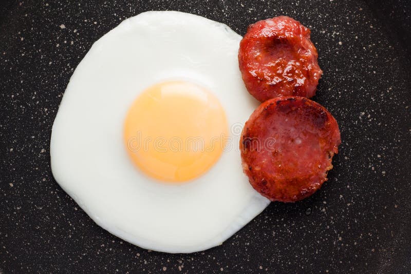 Breakfast on the Table. Fried Eggs with Fried Sausages Salami and Dill