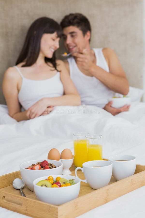 Man feeding breakfast cereals to women in bedroom. Man feeding breakfast cereals to women in bedroom