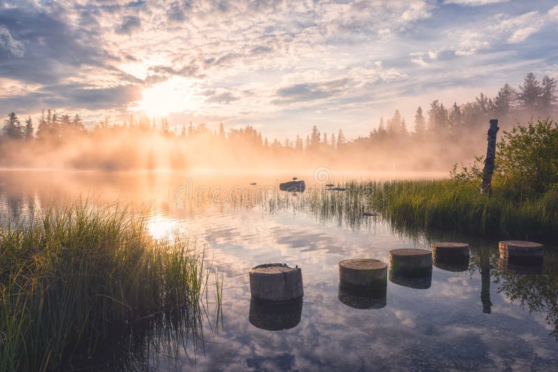 Úchvatný výhled na alpské jezero při východu slunce, mlhavá letní krajina, turistické středisko jezero štrbské pleso, vysoké tatry, slovensko