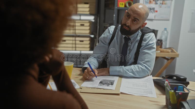 Bred man som intervjuar kvinnor på kontoret med pappersarbete som innebär en formell utredning eller utredning royaltyfria bilder