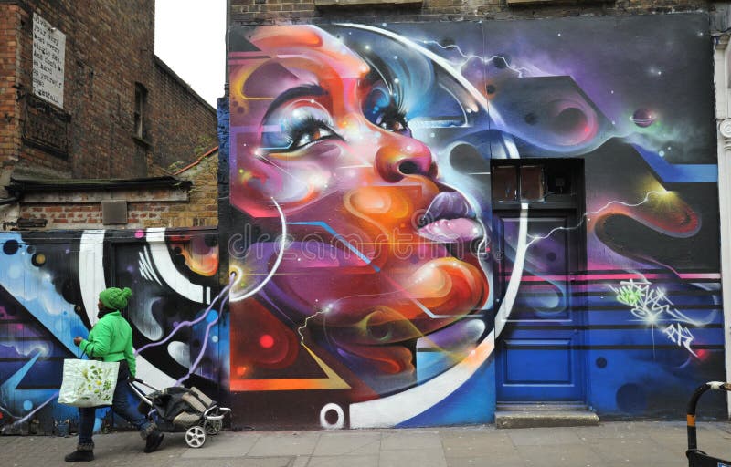 Brick Lane street in East London , the home of the graffiti artists from around the world . Amazing art done by Dale Grimshaw , a famous writer who paints ethnic portraits . Muslim woman walking in a muslim district in London , England